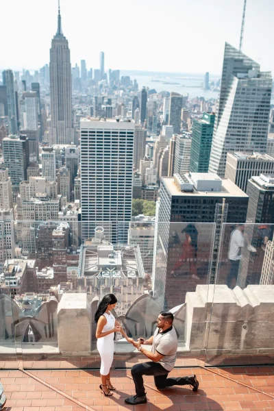 Stunning wide-angle view of a marriage proposal at Top of the Rock, with New York City’s skyline, including the Empire State Building, stretching out behind the couple. An unforgettable engagement moment captured from one of the best proposal spots in NYC.