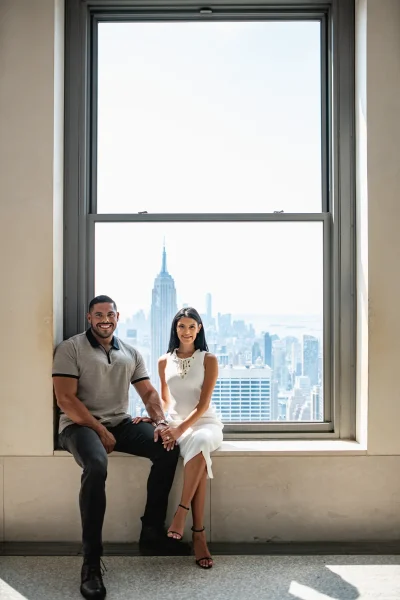 Romantic engagement photo at Rockefeller Center observation deck after a proposal at Top of the Rock with Empire State Building on the background