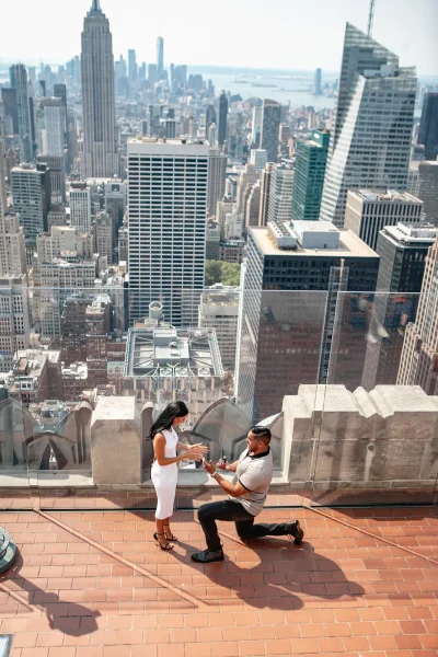 Emotional proposal moment at Top of the Rock with Empire State Building view, perfect NYC engagement spot during morning hours