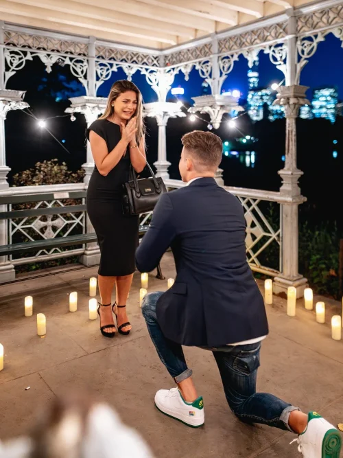Man kneeling to propose inside the candlelit Ladies Pavilion in Central Park at night