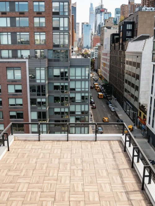 Private Midtown rooftop terrace with a wooden deck and railing overlooking a Manhattan avenue