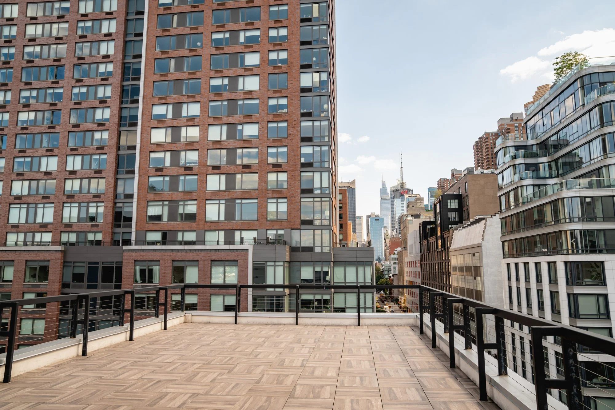 Wide wooden rooftop deck in Midtown Manhattan with high-rises and the skyline on a sunny day